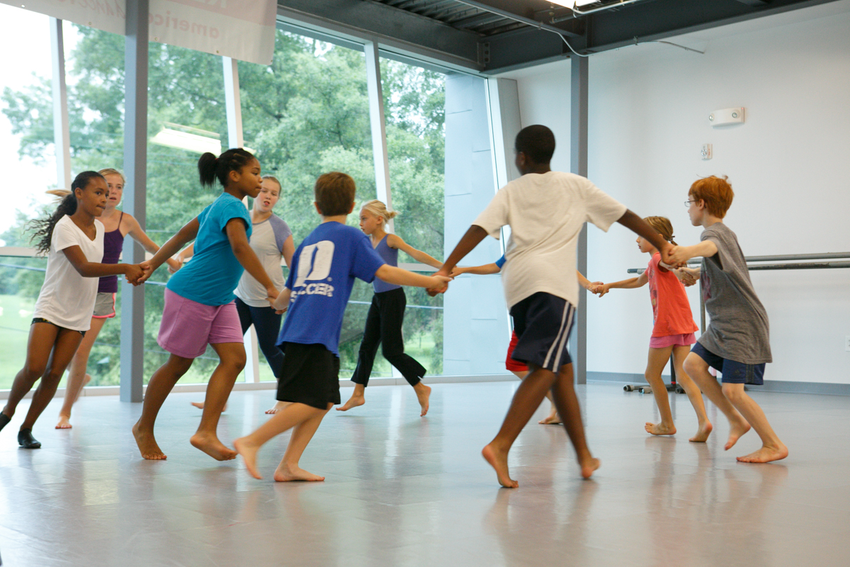 ADF youth class students holding hands and dancing in a circle