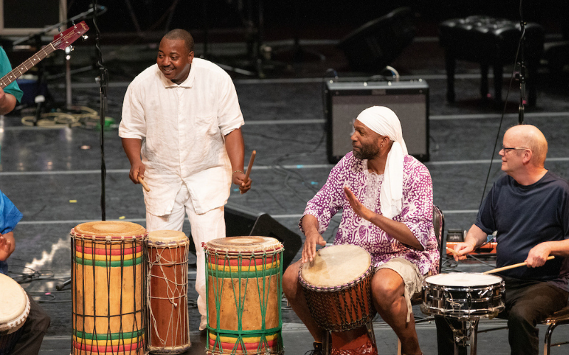 3 musicians playing the drums on stage