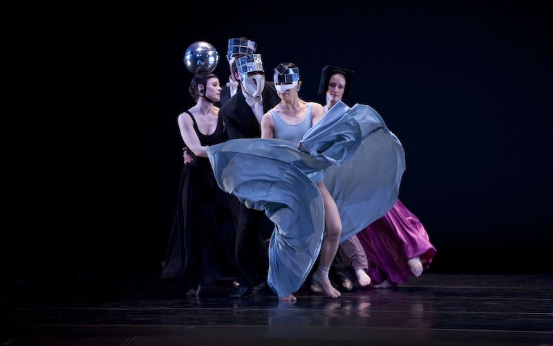 Dancers in long dresses and suits wear shiny headpieces