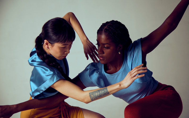 Two dancers in blue shirts pose together with arms overlapping