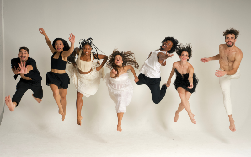 7 dancers jumping in a white room.