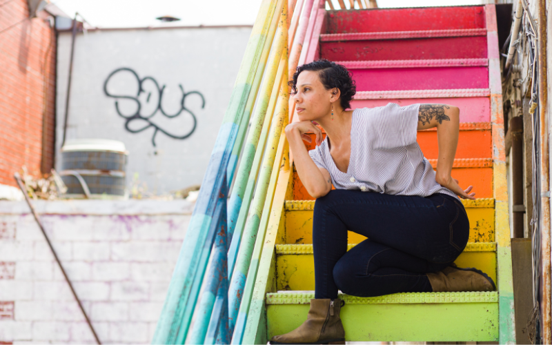 Cara Hagan sits on a rainbow-colored staircase.