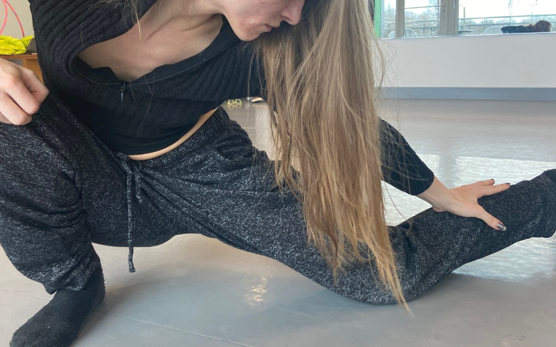 A close-up on a dancer in a deep lunge in a dance studio.